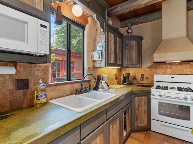 kitchen featuring white appliances, premium range hood, beam ceiling, a sink, and decorative backsplash