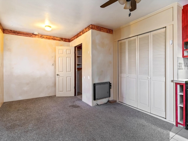 unfurnished bedroom with heating unit, ceiling fan, carpet, and a closet