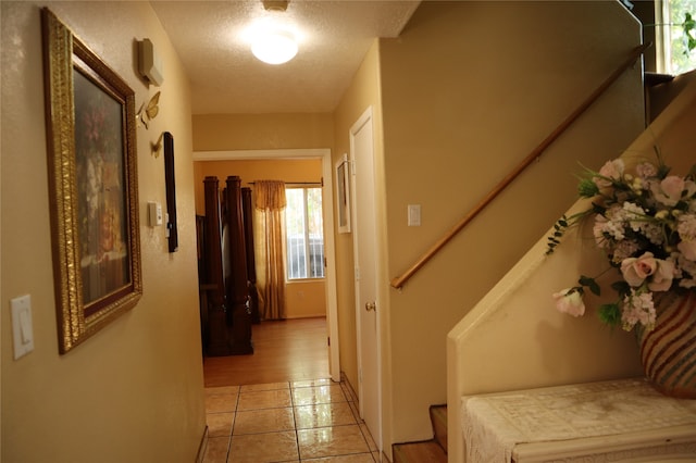 corridor with a textured ceiling and light tile patterned flooring