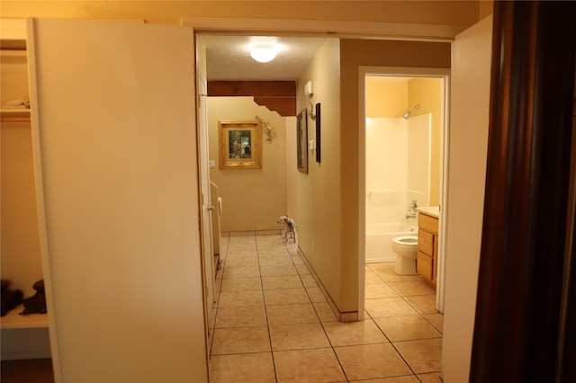 hallway featuring a textured ceiling and light tile patterned floors