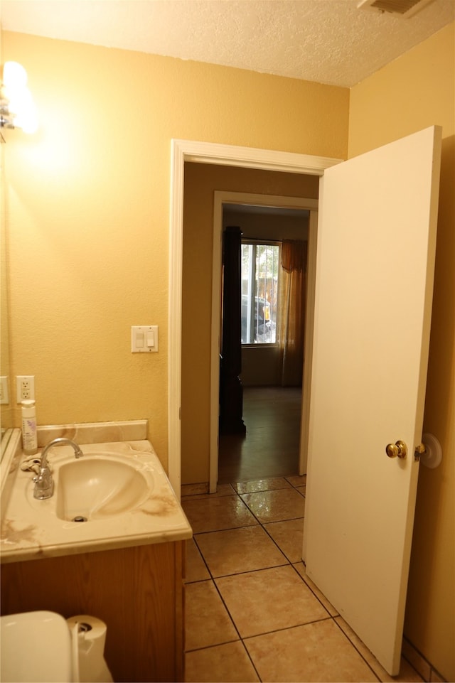 bathroom with tile patterned flooring, a textured ceiling, and vanity