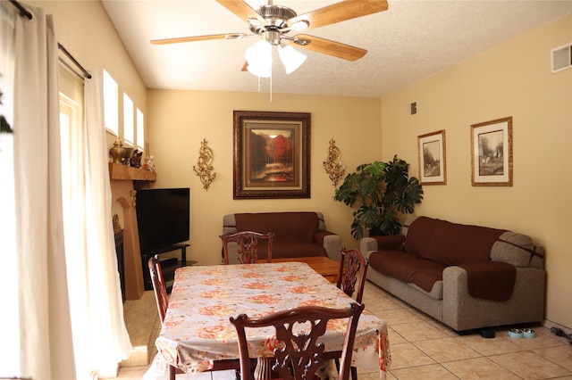 tiled dining space with a textured ceiling and ceiling fan