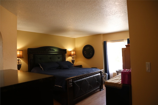 bedroom with a textured ceiling and hardwood / wood-style flooring