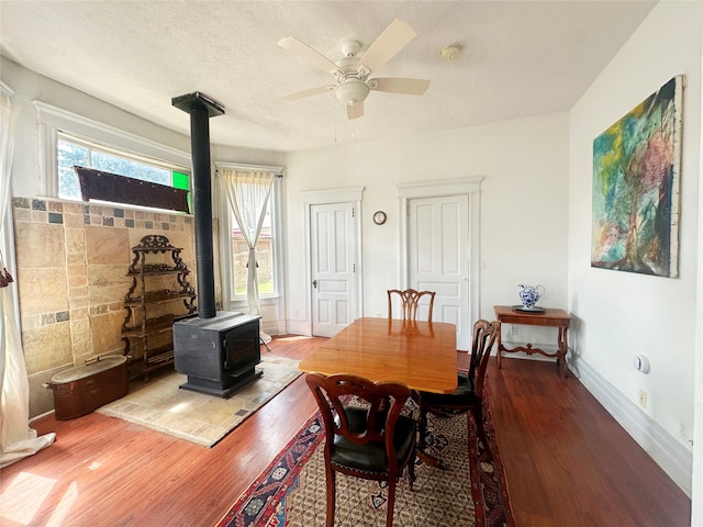 dining room featuring a wealth of natural light, hardwood / wood-style floors, and a wood stove