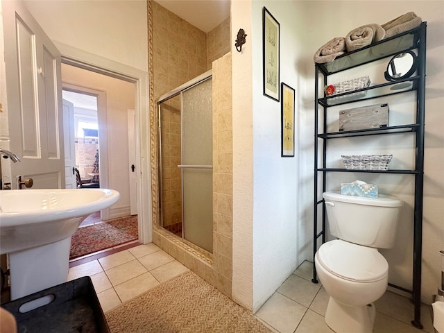 bathroom with tile patterned flooring, toilet, and a shower with door