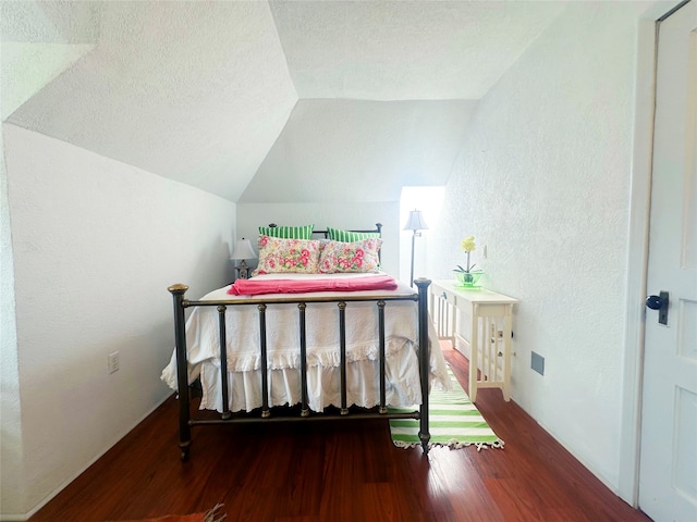 bedroom with hardwood / wood-style flooring, a textured ceiling, and lofted ceiling