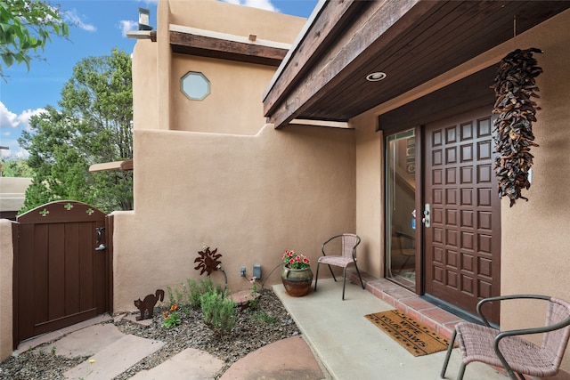 view of exterior entry with a gate and stucco siding