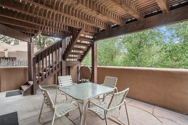 view of patio featuring outdoor dining space, fence, stairway, and a pergola