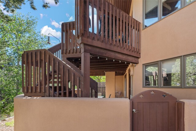 exterior space with a gate, stairs, fence, and stucco siding