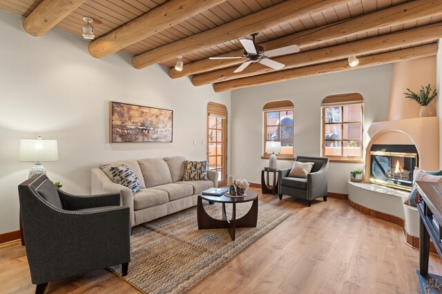 unfurnished living room with beam ceiling, track lighting, wood ceiling, and light hardwood / wood-style floors