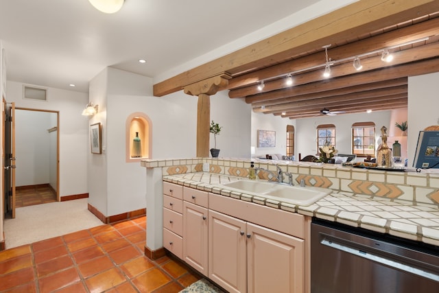 kitchen with a sink, open floor plan, stainless steel dishwasher, beam ceiling, and tile counters