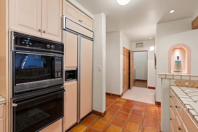 kitchen featuring dobule oven black, visible vents, tile counters, paneled fridge, and recessed lighting