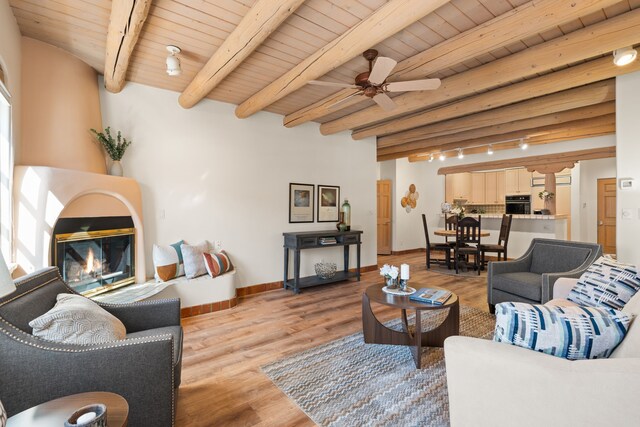 unfurnished living room with beamed ceiling, wood-type flooring, rail lighting, ceiling fan, and wood ceiling