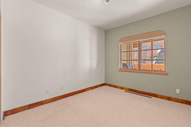 carpeted spare room featuring visible vents and baseboards