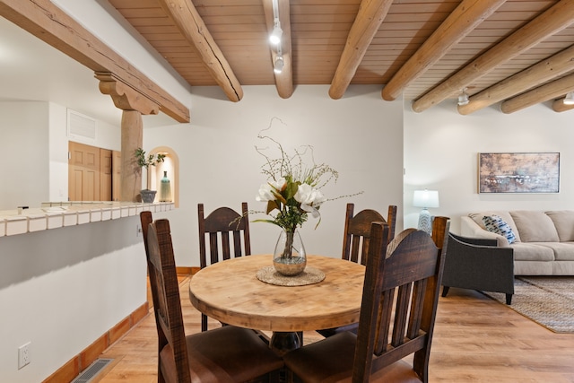 dining space with wooden ceiling, rail lighting, light wood-style flooring, and beam ceiling