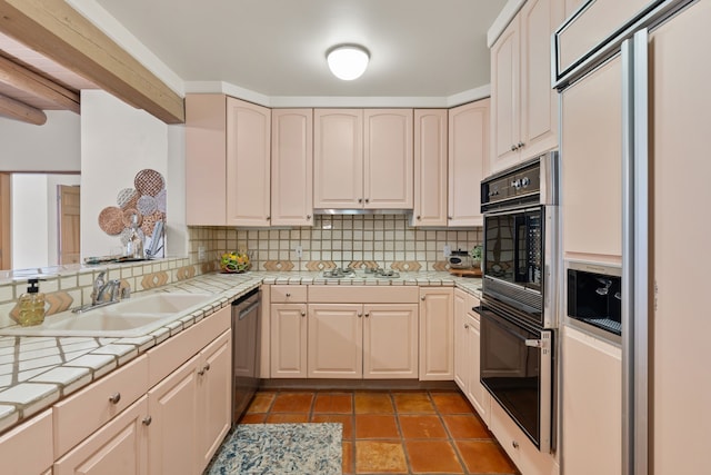 kitchen featuring tile countertops, a sink, dishwasher, and oven