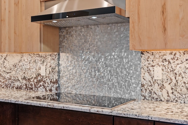 kitchen with light stone counters, wall chimney exhaust hood, and tasteful backsplash