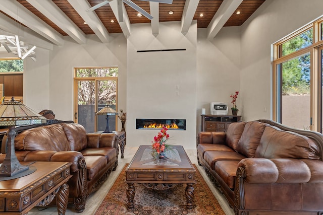 living room with wooden ceiling, beamed ceiling, a high ceiling, and ceiling fan