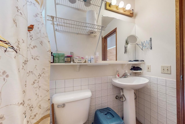 bathroom featuring toilet, curtained shower, and tile walls