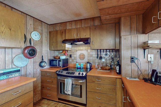 kitchen with appliances with stainless steel finishes, backsplash, and wood walls