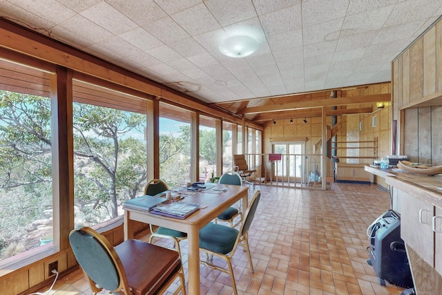 dining space with wood walls and a drop ceiling