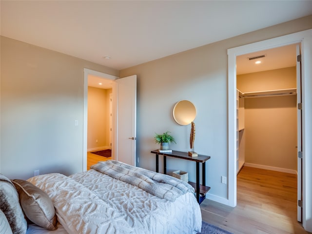 bedroom with a closet, a spacious closet, and light hardwood / wood-style flooring