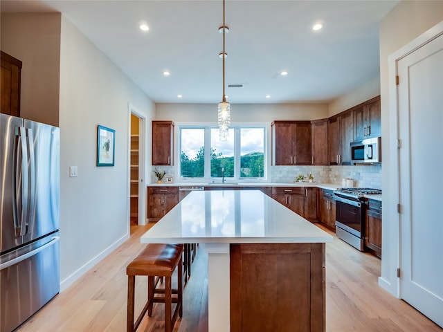 kitchen featuring pendant lighting, a center island, light hardwood / wood-style flooring, tasteful backsplash, and stainless steel appliances