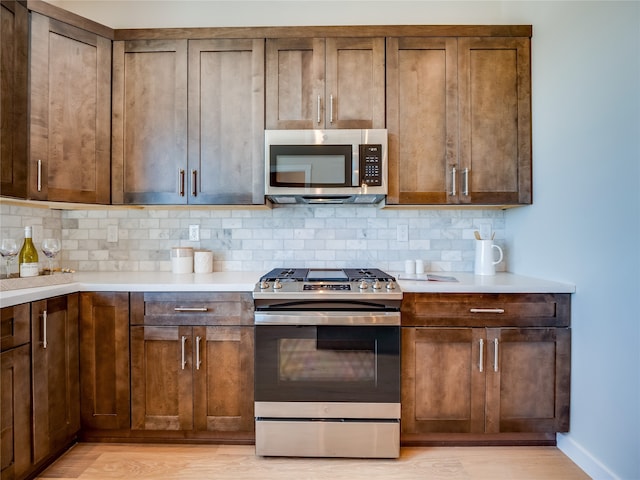 kitchen with decorative backsplash, stainless steel appliances, and light wood-type flooring