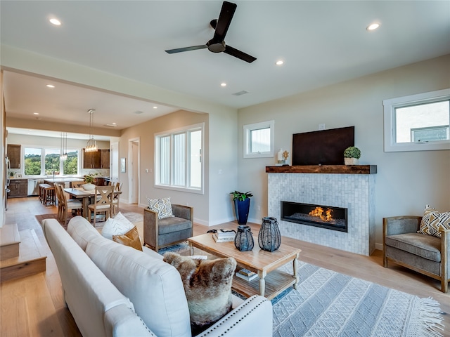 living room featuring ceiling fan, a fireplace, and light hardwood / wood-style flooring