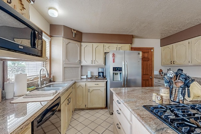 kitchen with light tile patterned floors, a sink, a textured ceiling, light stone countertops, and black appliances