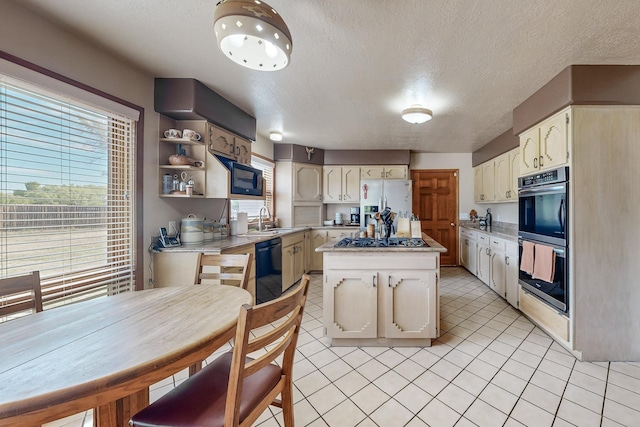 kitchen with light tile patterned floors, a kitchen island, light countertops, black appliances, and a sink