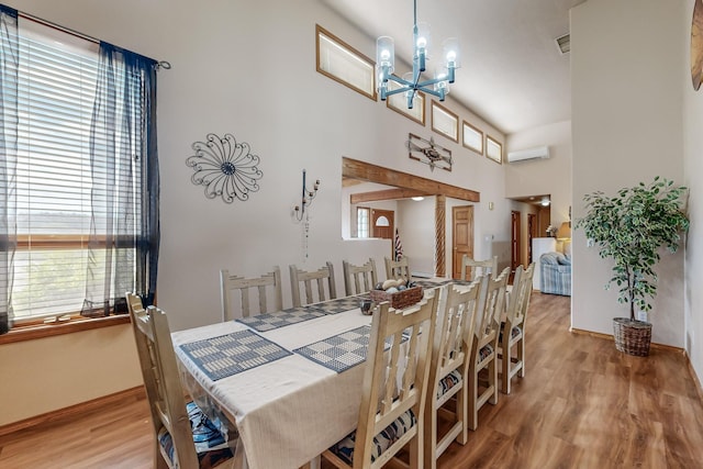 dining area with an AC wall unit, a notable chandelier, plenty of natural light, and light wood finished floors