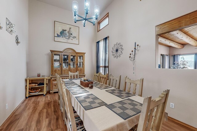 dining room featuring wood ceiling, wood finished floors, beamed ceiling, an inviting chandelier, and a high ceiling