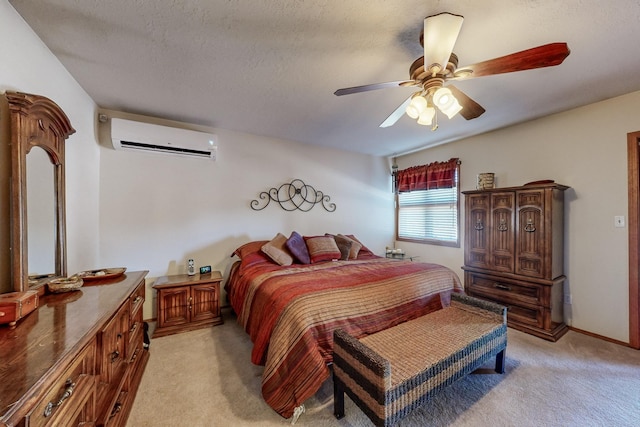 bedroom with ceiling fan, a textured ceiling, light carpet, baseboards, and a wall mounted air conditioner