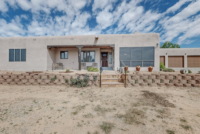 rear view of property with an attached garage and stucco siding