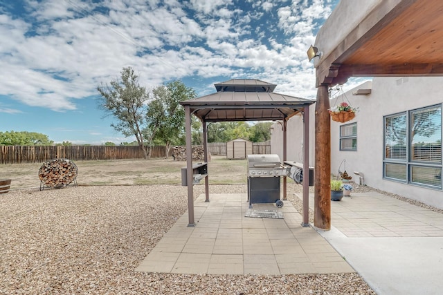 view of patio / terrace with a storage unit, a gazebo, a grill, a fenced backyard, and an outdoor structure