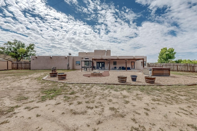 back of property with an outdoor fire pit, a fenced backyard, a patio, and stucco siding