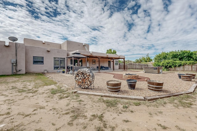 back of property with a gazebo, a fenced backyard, a fire pit, and a patio