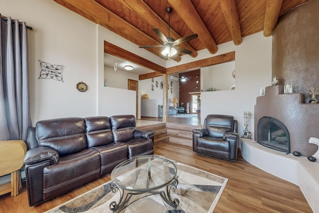 living room featuring a fireplace with raised hearth, ceiling fan, wood ceiling, light wood-type flooring, and beamed ceiling