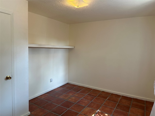 tiled spare room featuring a textured ceiling