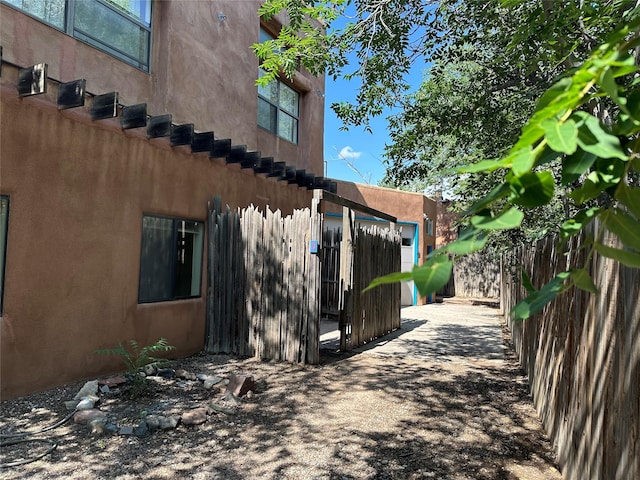 view of side of home featuring fence and stucco siding