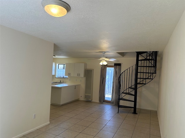 interior space featuring ceiling fan, light tile patterned floors, sink, and a textured ceiling