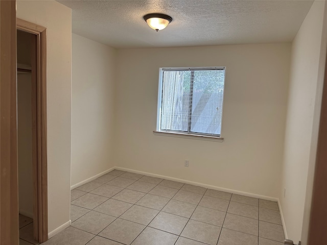 tiled empty room featuring a textured ceiling