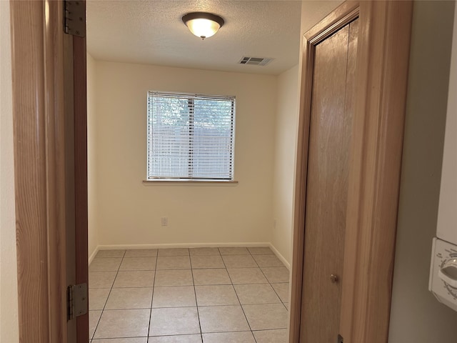 tiled empty room featuring a textured ceiling