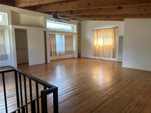 empty room with hardwood / wood-style floors, beam ceiling, and a ceiling fan