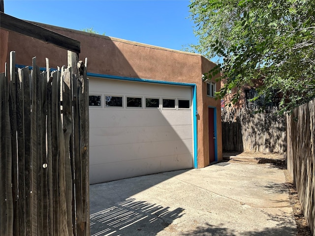 garage featuring concrete driveway and fence