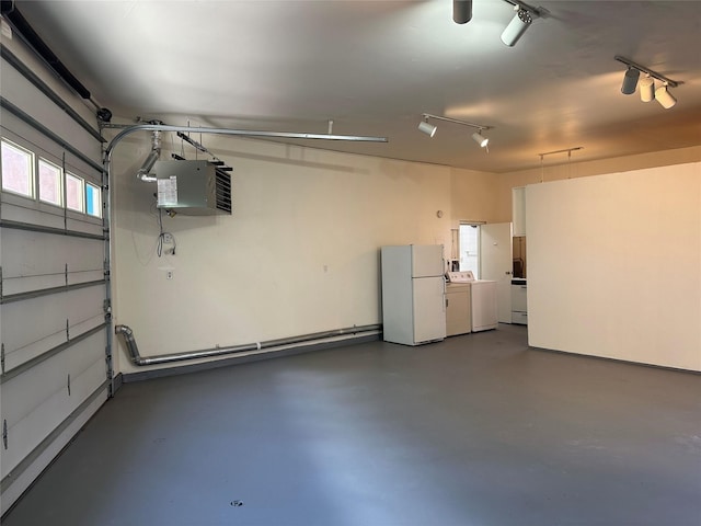 garage featuring freestanding refrigerator, washing machine and dryer, and a heating unit