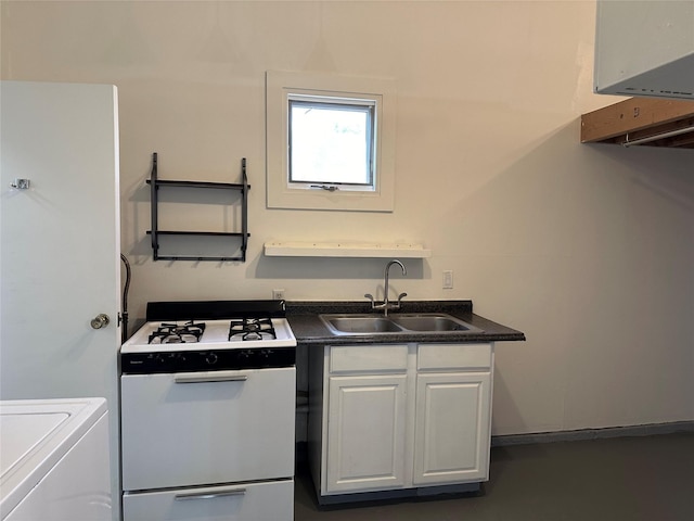 kitchen with white gas range, dark countertops, white cabinets, a sink, and washer / dryer