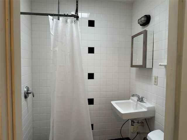 bathroom featuring toilet, tile walls, curtained shower, and sink