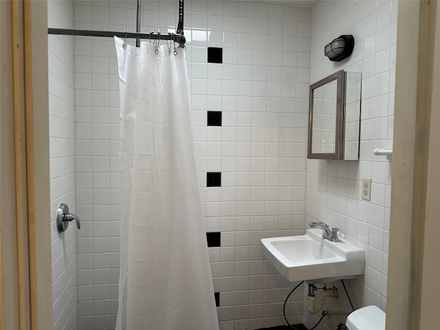 full bathroom featuring a tile shower, a sink, and tile walls